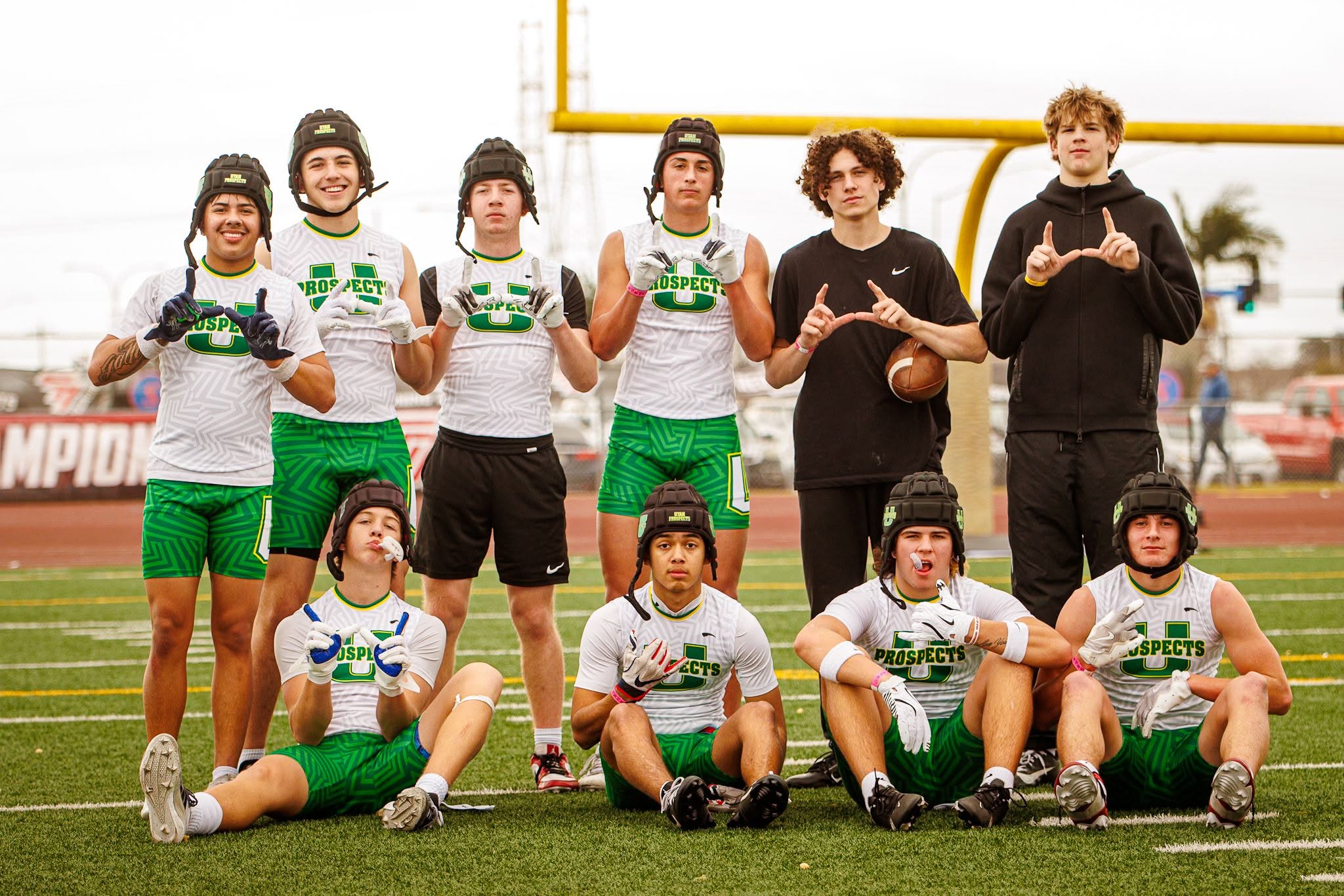 The Utah Prospects squad on the field throwing the U sign in white jerseys and green shorts